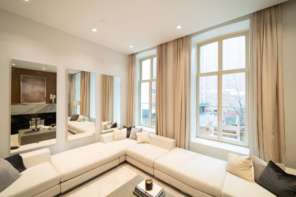 Bright and modern living room with high ceilings and large arched energy-efficient windows with beige floor-length curtains that allow natural light to fill the space with soft lighting, creating an inviting and comfortable atmosphere.