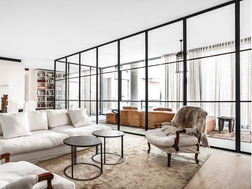 Elegant living room with black-framed glass partitions separating the seating area from the rest of the space.