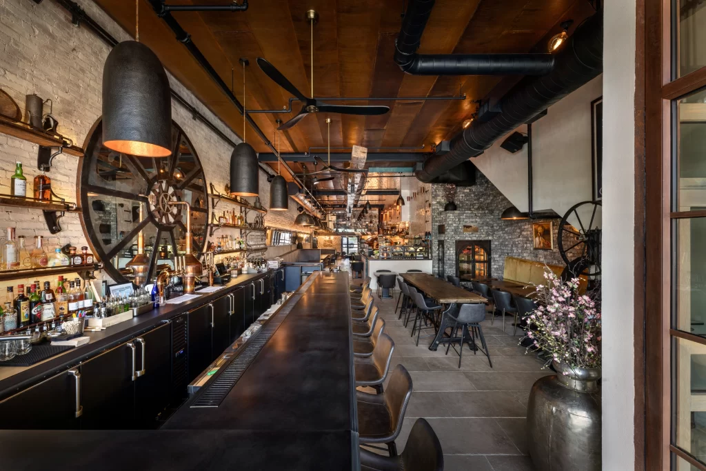 Beautifully designed industrial-style restaurant or bar space, combining raw materials with elegant modern touches that strikes a balance between functionality and aesthetics, making it a vibrant yet comfortable space.